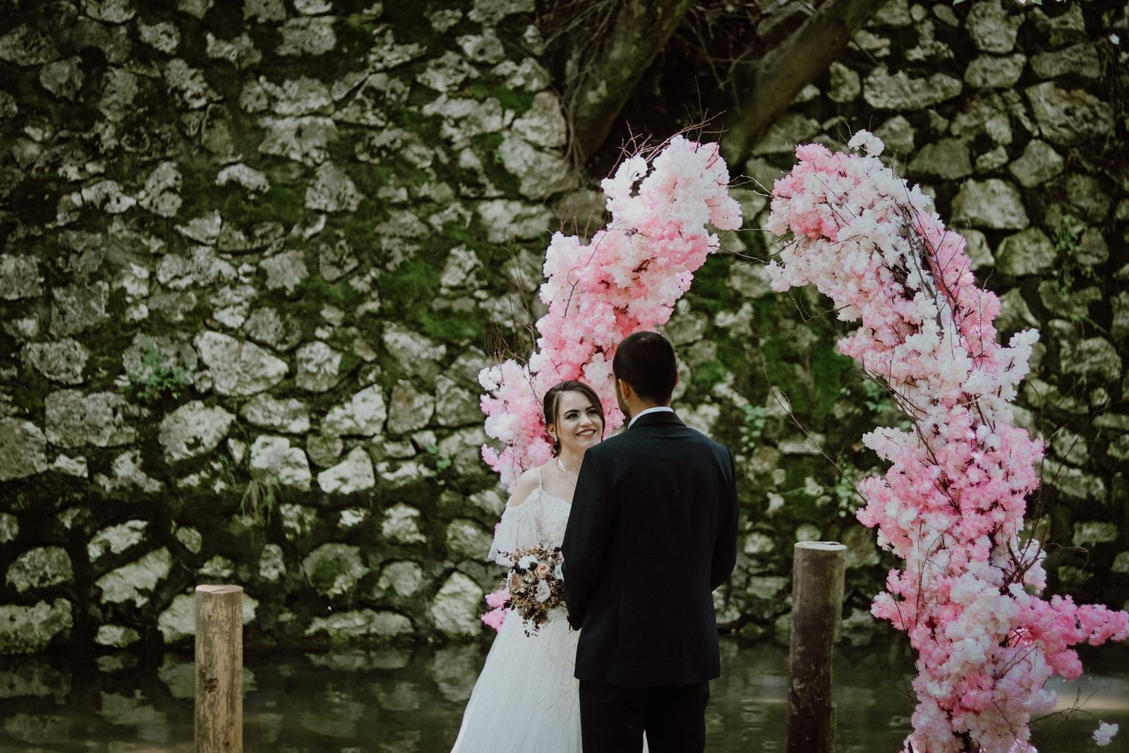 Bride and groom exchanging vows beneath a blossom arch