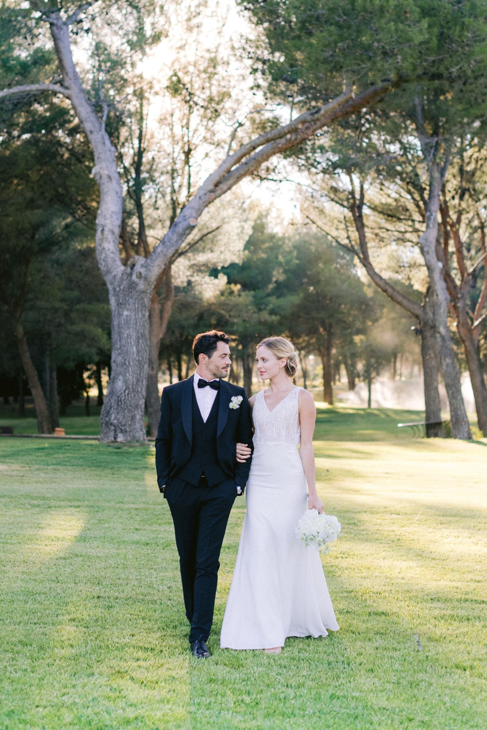 Walking arm in arm across the lawn beneath the trees