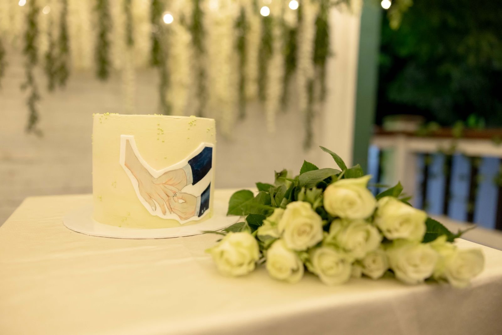 The ivory wedding cake beside white roses